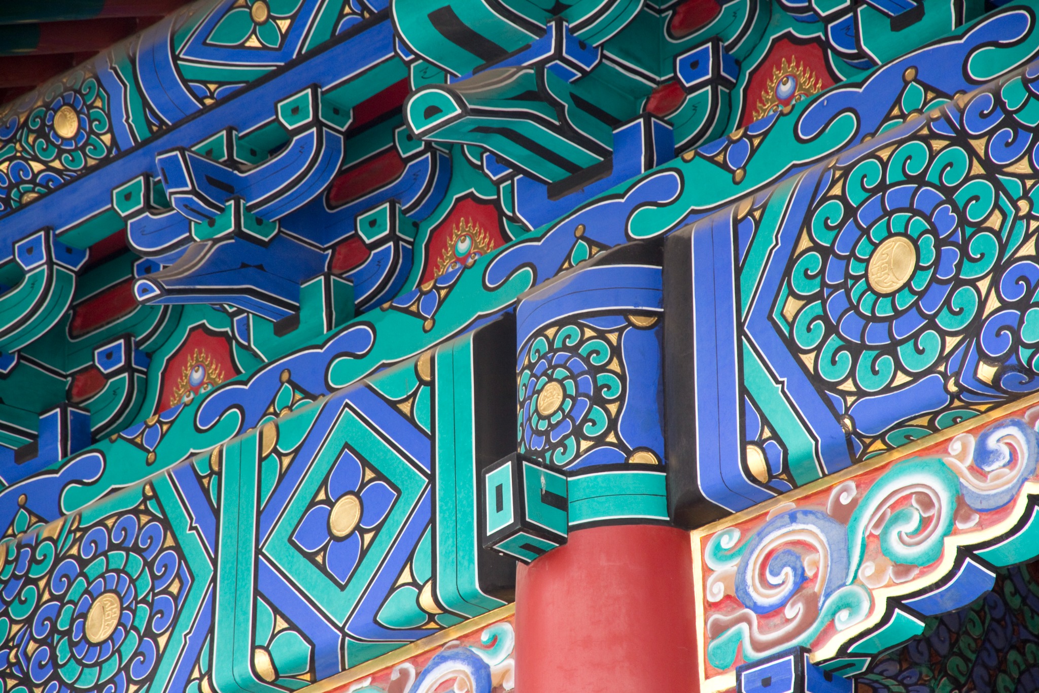 Detailaufnahme farbig gefasster chinesischer Architektur mit blau-grünen Ornamenten und roter Säule
